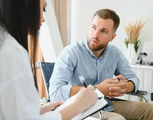 Addiction psychiatrist taking notes while talking with a patient during a consultation