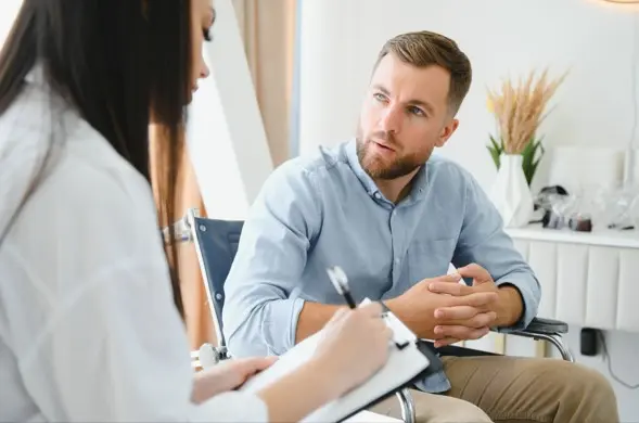 Addiction psychiatrist taking notes while talking with a patient during a consultation